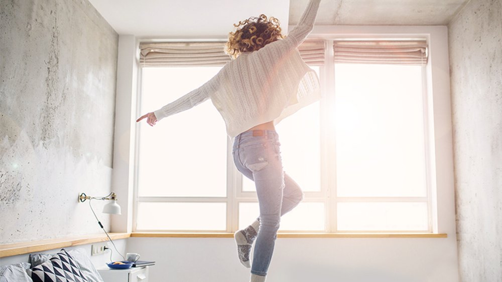 Une femme qui danse devant une fenêtre, dans la lumière du soleil